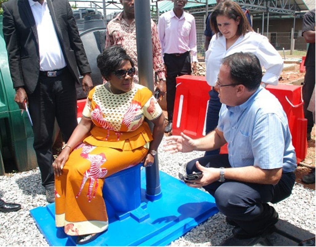 Minister for Sanitation and Water Resources, Cecelia Dapaah, seated on the Digni-Loo, with Country Director Alberto Wilde next to her