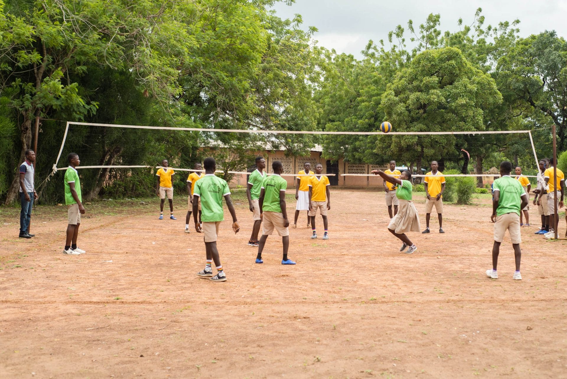 Photo of mixed gender school kids playing volleyball.