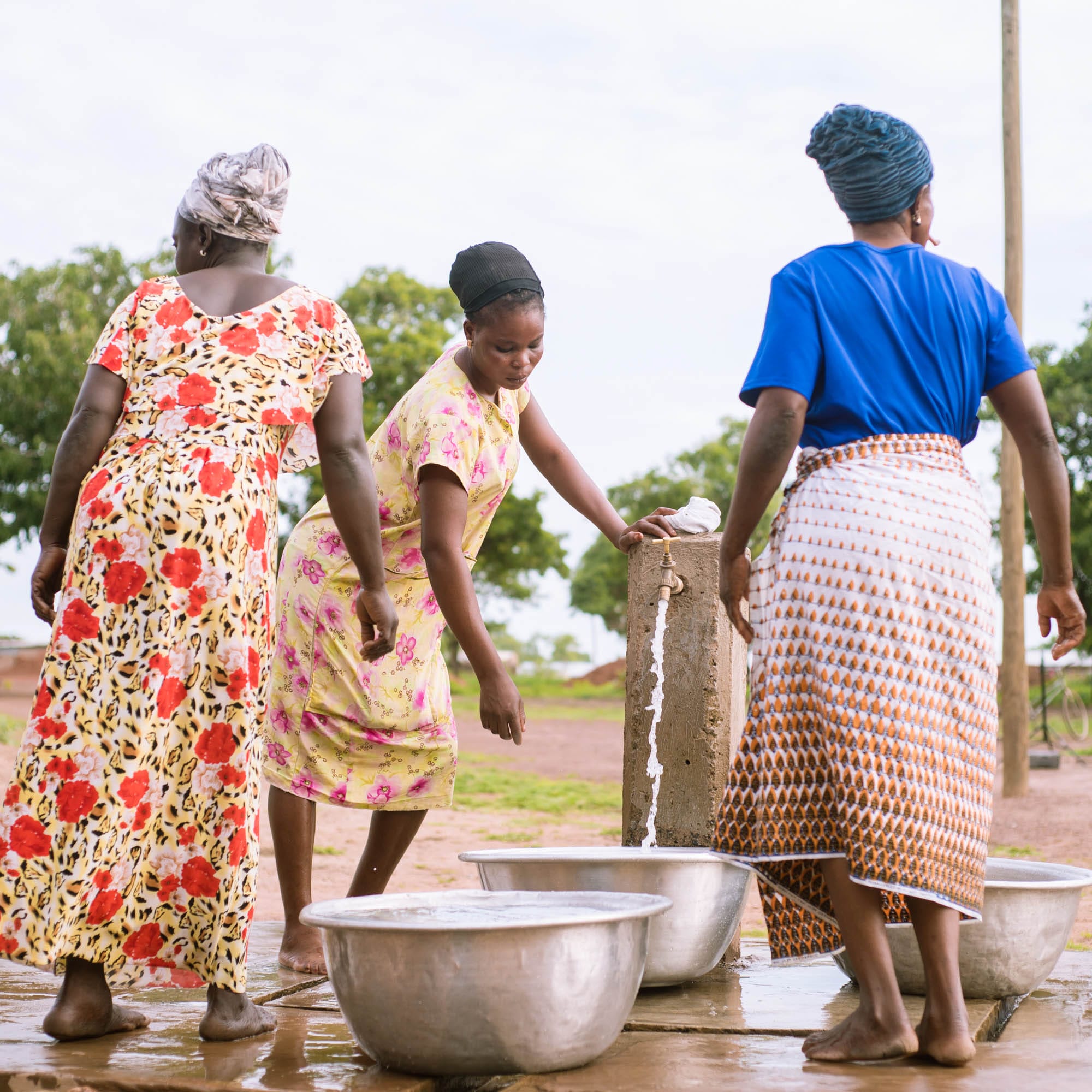 Three women fetching water from a standpipe