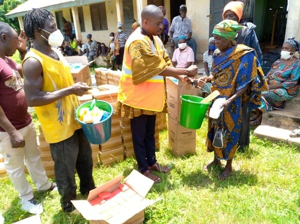 An elderly woman (flood victim) receiving a bucket with soap and other relief items