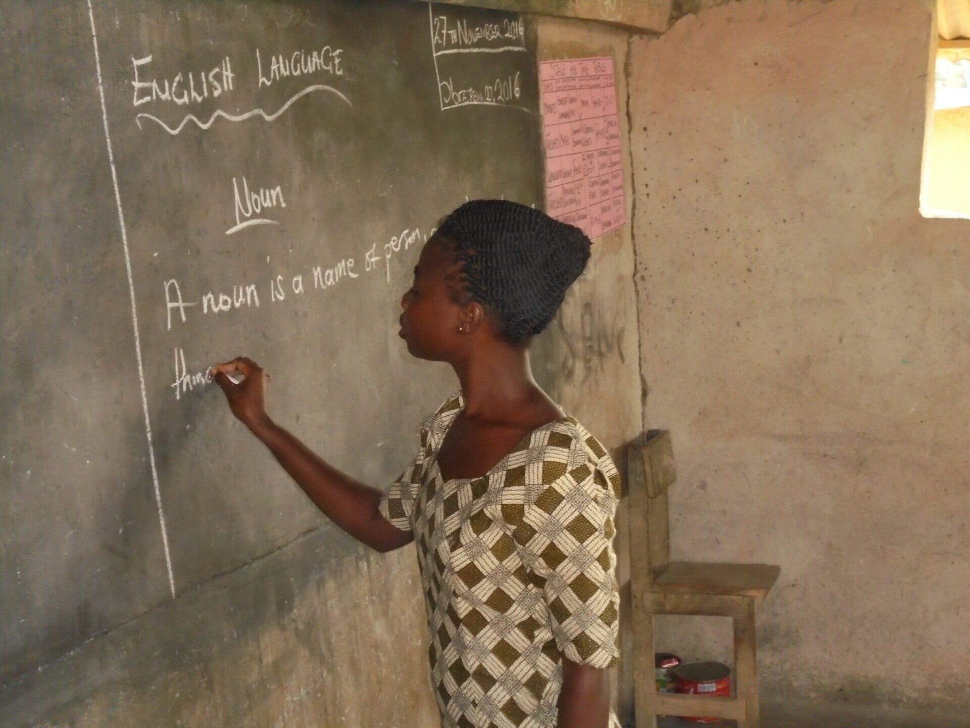 Former primary school teacher writes on the blackboard.